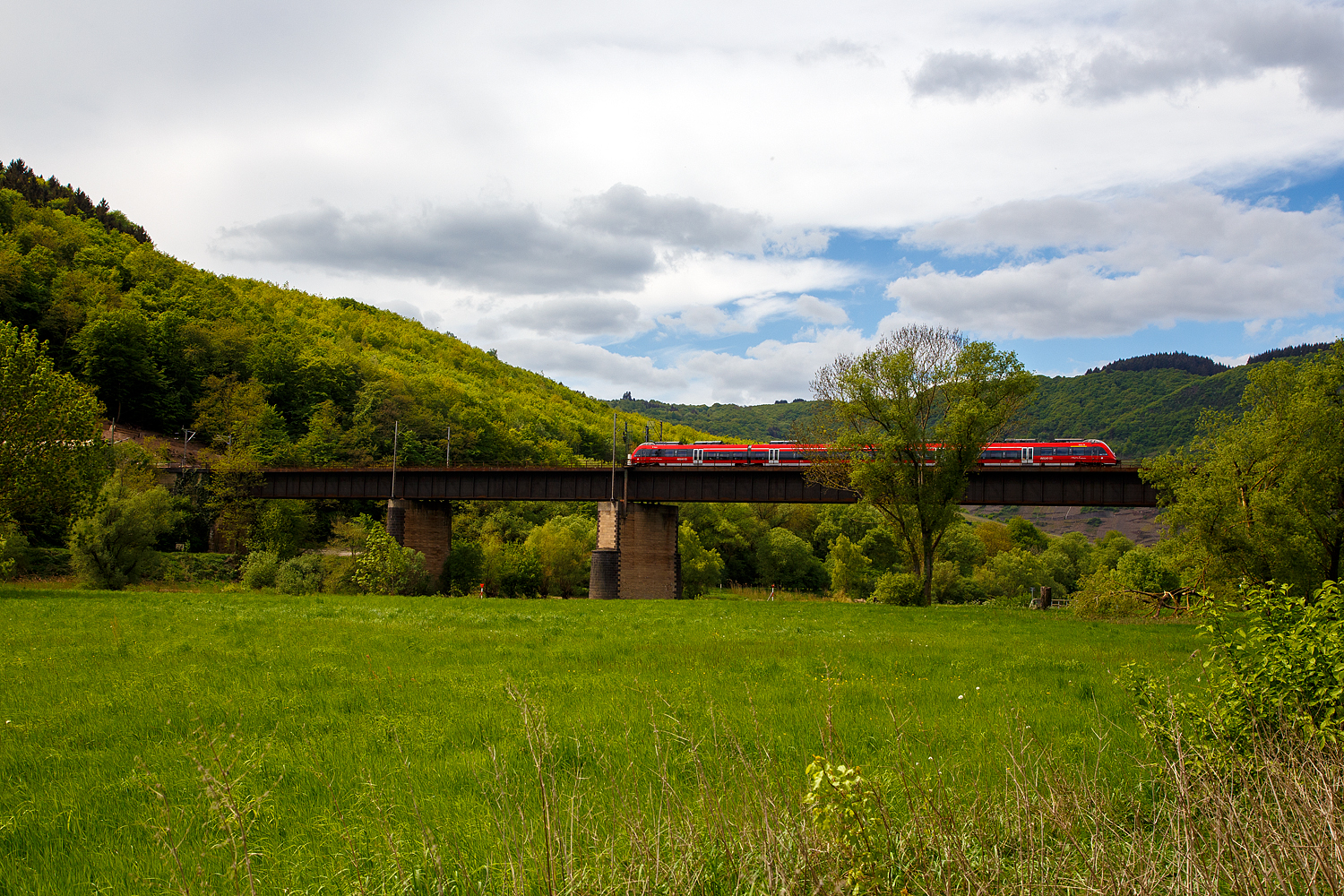 Ein vierteiliger Bombardier Talent 2 fährt am 28 April 2018, als RB 81  Moseltalbahn  (Trier – Cochem – Koblenz), bei Ediger-Eller über die 281 m lange Moselbrücke und erreicht bald den Bahnhof Ediger-Eller.