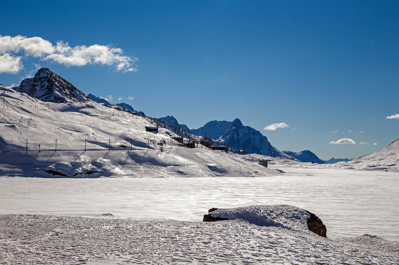 Ein winterlicher letzter Blick aus dem Bernina-Zug über den Lago Bianco hinweg auf Ospizio Bernina am 20 Februar 2017. Durch den Schnee auf dem zugefrorenen Lago Bianco ist dieser hier wahrhaft weiß. 

Der RhB Bahnhof Ospizio Bernina (Bernina-Hospiz) ist mit 2.253 m ü. M. die höchstgelegene Bahnstation im Netz der Rhätischen Bahn und damit auch die höchste Eisenbahn-Alpenüberquerung und das sogar als reine Adhäsionsbahn.
