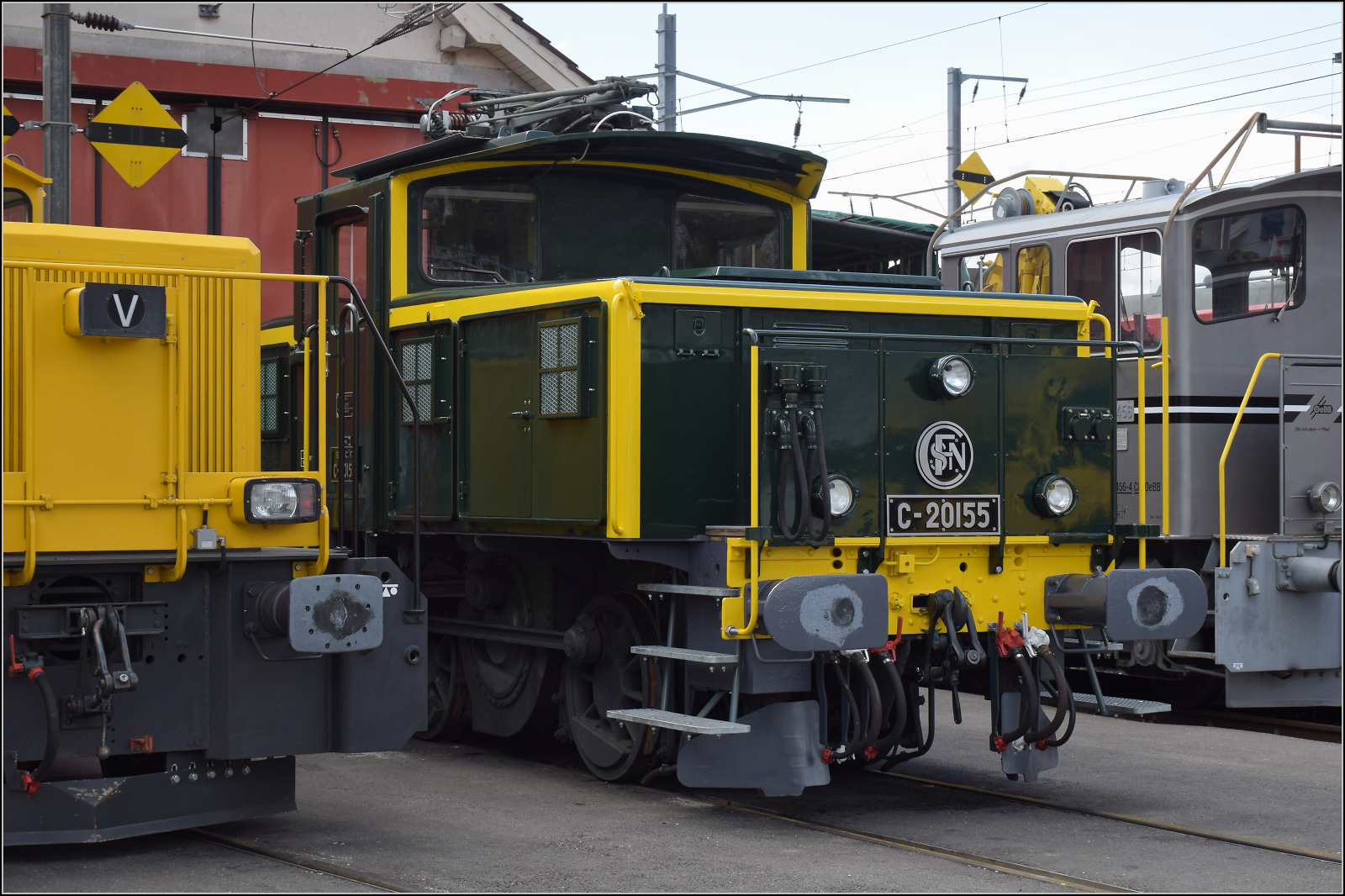 Etwas versteckt vor der Werkstatt in Balsthal steht die wunderbar in den Originalzustand zurückversetzte Zweispannungsrangierlok Ee 3/3 16515. Die letzte erhaltene Rangierlok dieser Baureihe war zu Beginn ihrer Karriere von den SNCF trotz sehr niedriger Höchstgeschwindigkeit im Streckendienst nach Basel eingesetzt. Weil sie doch im Rangierdienst besser geeignet ist, kam sie ein Jahrzehnt später zu den SBB als Ergänzung in den Rangierdienst. Ende letzten Jahres bekam sie ihr altes Farbkleid und die Bezeichnung C 20155 zurück. Nicht ganz unumstritten, aber meiner Meinung nach eine schöne Idee und wunderbar anzusehen. Balsthal, April 2025.
