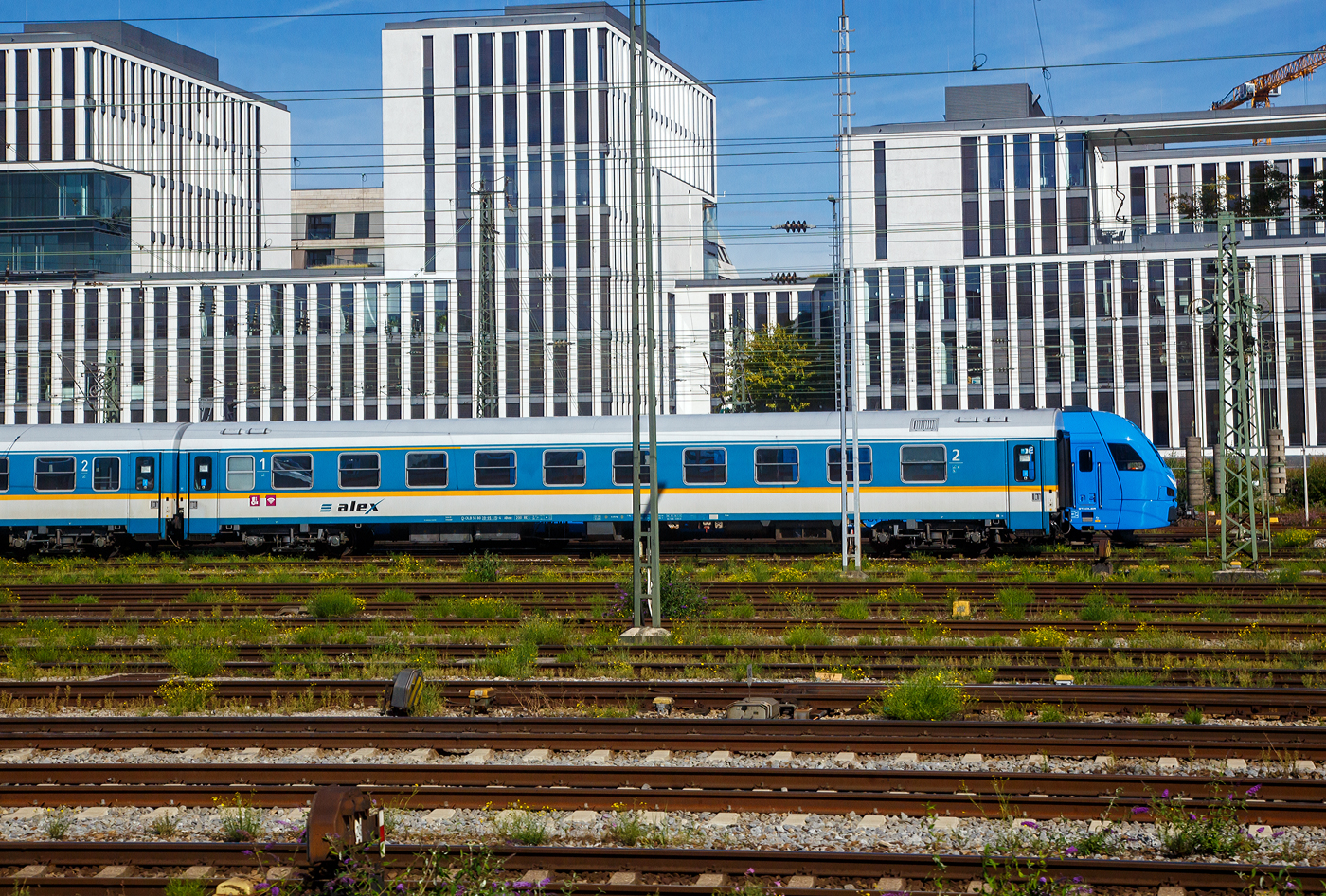 Ist das der neue alex-FLIRT 3.....Nein, ein FLIRT 3 steht nur hinter dem abgestellten alex-Zug.  Der 1./2. Reisezugwagen D-DLB 56 80 39-95 515-4, der Gattung ABvmz, der Die Länderbahn GmbH (alex) abgestellt am 13.09.2022 beim Hbf München. Der Wagen ist der ex DR 51 80 20-95 515 (Amz), ex 51 80 20-95 515-0 D-DB (Bomz 210.2). Aufnahme aus einem einfahrenden IC heraus.

TECHNISCHE DATEN:
Hersteller:  Waggonbau Bautzen (Umbau VIS Halberstadt)
Spurweite: 1.435 mm
Länge über Puffer: 26.400 mm
Wagenkastenlänge: 26.100 mm
Drehzapfenabstand: 19.000 mm
Achsstand im Drehgestell: 2.600 mm
Drehgestellbauart: GP 200-S-Mg
Leergewicht: 41 t
Höchstgeschwindigkeit: 200 km/h
Zulassungen für: RIC / D, A und CH (einspannungsfähig)
Sitzplätze: 20 in der 1. und 29 in der 2. Klasse, 2 Rollstuhlplätze
Abteile: 4 Abteile 1. Klasse; 4 Abteile 2. Klasse; 1 Mehrzweckabteil
Toiletten: 2, davon 1 behindertengerecht
Bremsbauart: KE-GPR-Mg

Die Wagen der ehemaligen Gattung Amz 210 und Amz 210.1 sind die jüngsten Fahrzeuge im Bestand des ALEX. Die Wagenserie entstand 1991 beim Waggonbau Bautzen (ehemals LOWA, später Deutsche Waggonbau AG (DWA), jetzt Bombardier) im Auftrag der Deutschen Reichsbahn. Sie entstanden nach dem Vorbild der Ame-Wagen des RAW Halberstadt (spätere Am 201) und den UIC-Z-Normen. Es wurden insgesamt 40 Wagen gebaut, die ab Werk im blauen Interregio-Farbschema lackiert waren, innen jedoch noch klassische Schnellzugwagen waren. Eingesetzt wurden sie bis 2002 im Interregioverkehr. Zum Schluss liefen sie teilweise noch in Regionalexpresszügen, im Jahr 2003 wurde diese Wagenserie (gerade einmal 12 Jahre alt!) komplett ausgemustert. 22 Wagen dieses Typs konnte die Regentalbahn von der DB kaufen, 2 Wagen wurden als Ersatzteilspender verwendet, so dass sich aktuell 20 Wagen im Bestand des ALEX befinden. 

Die Wagen besaßen ursprünglich 10 Abteile mit je 6 Sitzplätzen, beim ALEX wurden vier Abteile zur 1.Klasse mit je 5 Sitzplätzen, vier Abteile zur 2.Klasse mit je 6 Sitzplätzen, das zehnte Abteil entfiel zugunsten eines kleinen Mehrzweckbereichs. Einige Wagen laufen als rein zweitklassige Wagen.

Zur Einsetzbarkeit: Die Wagen mit den Ziffern 90 an 
der 7. und 8. Stelle der Wagennummer sind mehrspannungsfähig, die Wagen mit den Ziffern 95 an dieser Stelle (wie dieser hier) sind nur einspannungsfähig - die Versorgung der Zugsammelschiene ist nur mit der in Deutschland üblichen Spannung von 1000V und 16 2/3 Hz möglich
