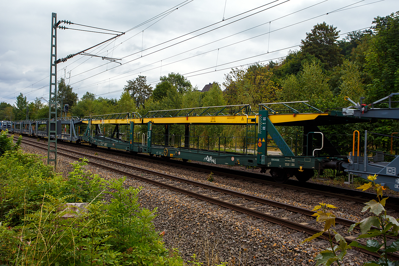 Leerer offener vierachsiger (2 x zweiachsiger) Doppelstock-Autotransportwagen, 27 80 4371 031-0 D-ARS, der Gattung Laaers 560.1 (BA 5.854), der ARS Altmann AG, am 22 Juli 2026 im Zugverband bei einer Zugdurchfahrt in Siegen-Eiserfeld.

Diese Waggons haben zwei Ladeebenen und sind f�r den europaweiten Transport geeignet. Sie werden f�r den internationalen Transport von PKWs, Gel�ndewagen, und Vans eingesetzt und bieten maximale Flexibilit�t durch eine stufenlos verstellbare obere Ladeebene. Aufgrund der hohen Lastgrenze (34t) ist der Transport von besonders schweren Fahrzeugen der genannten Typen m�glich. Damit sowohl ein typenreiner Transport als auch eine Mischverladung in den unterschiedlichen Ladema�en m�glich ist, kann die obere Ladeebene hinsichtlich der Transportstellungen stufenlos eingestellt werden.

Der Laaers 560.1 ist eine neu entwickelte Autotransportwageneinheit und besteht aus zwei zweiachsigen Wagenelementen, die mit einer im Betrieb nicht trennbaren Kurzkupplung (mit einer Bruchkraft von 1.000 kN) miteinander verbunden sind. Sie verf�gt �ber stufenlos verstellbare Hebe- und Senkeinrichtungen f�r die oberen Ladeebenen. Sowohl die beiden unteren als auch die beiden oberen Ladeebenen der Wageneinheit sind jeweils f�r 9 t Zuladung ausgelegt. Die Lastgrenze f�r die Wageneinheit betr�gt max. 34 t (je Wageneinheitsh�lfte 17 t). Die Struktur der Wageneinheiten ist f�r Pkw / Van mit einem Gesamtgewicht von 2800 kg und Radlasten von 1000 kg ausgelegt.

Die oberen Ladeebenen sind �ber jeweils vier dreig�ngige Spindeln und Trags�ulen mit dem Untergestell verbunden. Die S�ulenpaare lassen sich getrennt bedienen, damit die oberen Ladeebenen an den Fahrzeugenden - notwendig zur Be- und Entladung - rampenartig gestellt werden k�nnen. 

TECHNISCHE DATEN:
Gattung: Laaers 560.1 (BA 5.854),
Spurweite: 1.435 mm
Anzahl der Achsen: 4
L�nge �ber Puffer: 31.000 mm
Achsabst�nde: 10.000 mm / 5.160 mm / 10.000 mm
Laufraddurchmesser (neu): 840 mm (au�en) / 730 mm (mittleren)
Ladel�nge: 30.070 mm (unten) / 30.550 mm (oben)
H�chstgeschwindigkeit: 100 km/h (120 km/h leer)
Eigengewicht: 30.000 kg
Nutzlast: 34,0 t ab Streckenklasse B (max. 17 t pro Ebene)
Kleinster befahrb. Gleisbogenhalbmesser: 75 m
Bremse: KE-GP-A
Verwendungsf�higkeit: TEN GE
