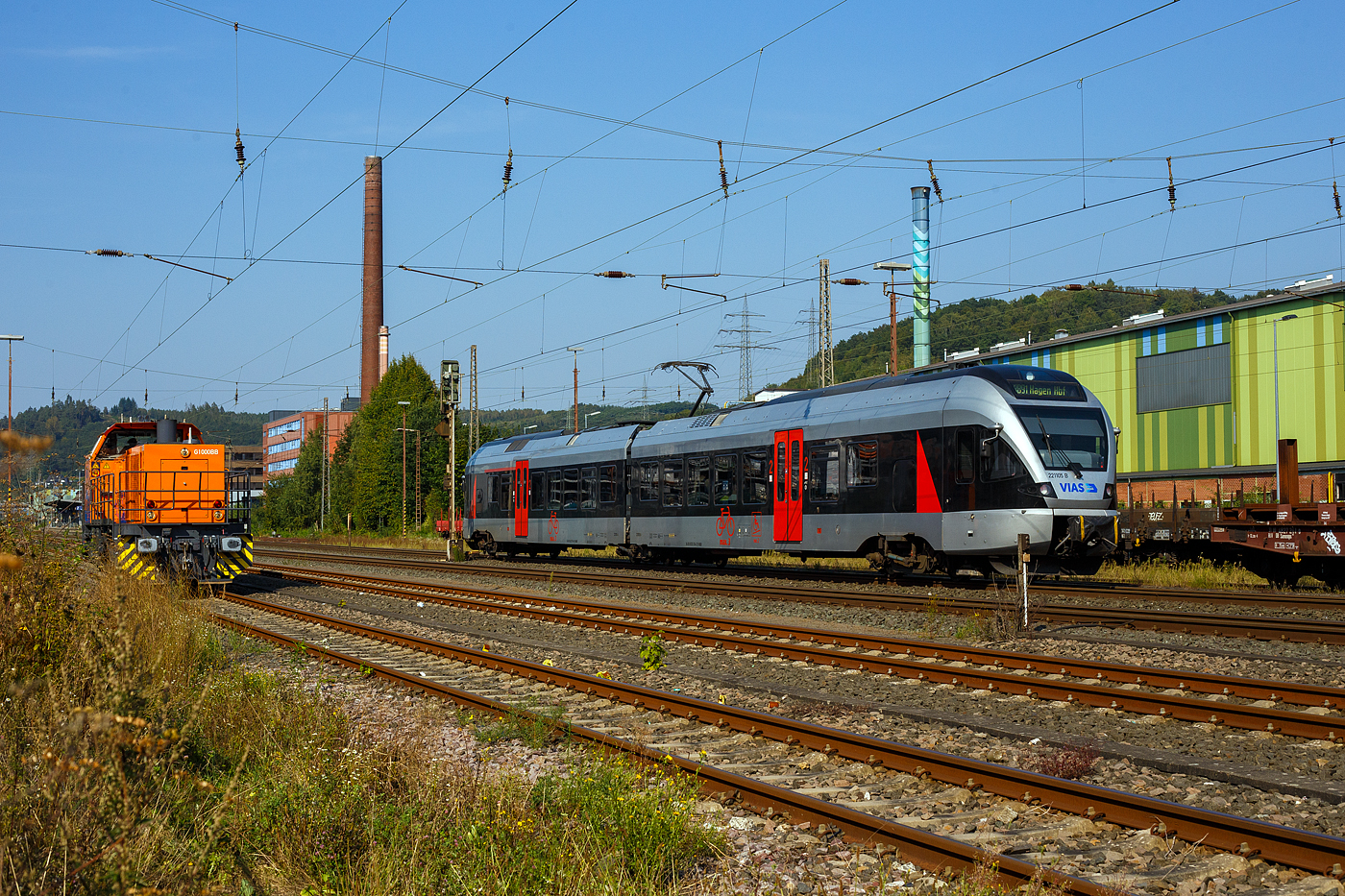 Nun mit VIAS-Logo....
Der für die VIAS Rail GmbH fahrende 2-teilige Stadler FLIRT VIAS ET 221105 (94 80 0426 104-6 D-VIASR / 94 80 0826 104-2 D-VIASR), ex DB 426 104-6 / 826 104-2, ex Abellio Rail NRW - ET 22 2105, fährt am 05 September 2024, als RB 91  Ruhr-Sieg-Bahn  von Siegen Hbf nach Hagen Hbf, durch Siegen-Geisweid und erreicht bald den Bahnhof Siegen-Geisweid.

Nach der Insolvenz der Abellio Rail NRW GmbH übernahm, zunächst per Direktvergabe wieder die DB Regio den Verkehr auf der Strecke bis Dezember 2023, seit dem Fahrplanwechsel im Dezember 2023 hat nun nach regulärer Vergabe schließlich die VIAS Rail GmbH den Schienenpersonennahverkehr (RE 16 / RB 91) bis Dezember 2034 übernommen. VIAS Rail ist ein 100 %iges Tochterunternehmen der R.A.T.H.-Gruppe. Wobei die Triebzüge weiterhin der CBRail Leasing s.à.r.l. (Luxembourg) gehören und nun weiter von der VIAS Rail GmbH geleast sind.

Dieser Triebzug wurde 2007 von Stadler Pankow GmbH in Berlin unter den Fabriknummer 37662 gebaut.

Links auf dem Gleis steht die KSW 44 (92 80 1271 004-4 D-KSW) eine MaK G 1000 BB der KSW (Kreisbahn Siegen-Wittgenstein), die in der anderen Richtung die Überholung des RE 34 abwarten muss (was ich nicht ganz verstehe). Im Hintergrund das Stahlwerk der Deutschen Edelstahlwerke GmbH, zuvor Edelstahlwerke Südwestfalen.
