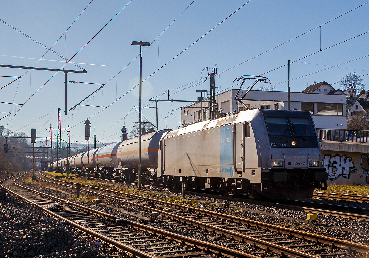 Nun sind die Schranken am Bü 343 geschlossen und sie hat Hp 1 oder 2...
Die 185 696-2 „Marie-Chanthou“ (91 80 6185 696-2 D-Rpool) der Railpool fährt am 14.02.2023 mit einem Druckgas-Kesselwagenzug über die Siegstrecke (KBS 460), durch Niederschelderhütte in Richtung Siegen.

Die TRAXX F140 AC2 wurde 2010 von Bombardier in Kassel unter der Fabriknummer 34722 gebaut und an die Railpool geliefert. Die Lok ist für Deutschland und Österreich zugelassen. Die ehemaligen Zulassungen für Schweden und Norwegen sind nun durchgestrichen.