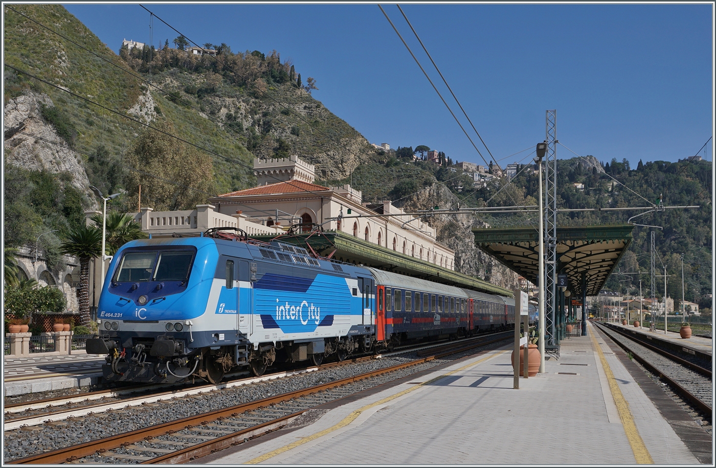 Praktisch an der selben Stelle wie beim vorangehenden Bild entstand dieses Foto: die FS Trenitalia E 464.231 (und die E 464.350 am Zugschluss) sind mit dem ICN 1959 von Roma Termini (23.25) nach Siracusa (an 12:52) unterwegs und haben pünktlich den Bahnhof von Taormina-Giardini erreicht. 

13. März 2026

