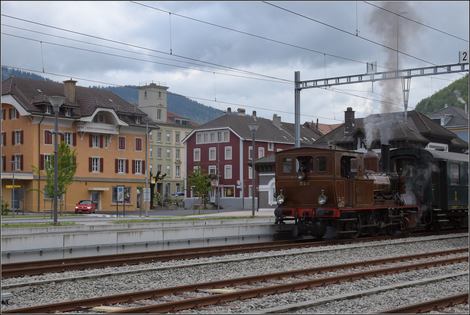 Vapeur Val-de-Travers: Train du Terroir.

Mit Blick in den Ort Fleurier wartet E 3/3 8511 auf den Gegenzug. Mai 2023.