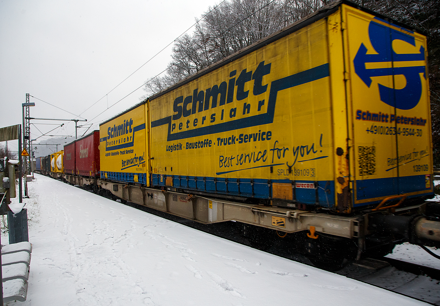 Vierachsiger Drehgestell-Containertragwagen der Gattung Sgmnss, 33 85 4578 226 CH-HUPAC, der HUPAC AG, beladen mit 2 Wechselbrücken, am 19.01.2023 im Zugverband bei der Durchfahrt in Scheuerfeld (Sieg) in Richtung Köln.

TECHNISCHE DATEN:
Hersteller: Ferriere Cattaneo SA (Schweiz)
Spurweite: 1.435 mm
Länge über Puffer: 17.340 mm
Drehzapfenabstand: 12.200 mm
Achsabstand in den Drehgestellen: 1.800 mm
Laufraddurchmesser: 920 mm (neu)
Ladelänge: 16.000 mm
Höhe der Ladeebene über S.O.: 1.115 mm
Eigengewicht: 16.500 kg
Max. Zuladung bei Lastgrenze S: 73,5 t (ab Streckenklasse D)
Max. Zuladung bei Lastgrenze SS: 63,5 t (ab Streckenklasse C)
Max. Geschwindigkeit: 100 km/h (Lastgrenze SS und leer 120 km/h)
Kleinster befahrbarer Gleisbogen: R 75 m
Bremse: KE-GP-A
Bremssohle: Jurid 816M
Feststellbremse: Ja
Verwendungsfähigkeit: TEN-GE

Die Bedeutung der Gattungs- und Kennbuchstaben (hier Sgmnss):
S - Drehgestellflachwagen in Sonderbauart
g - für den Transport von Containern mit einer Gesamtladelänge bis 60 Fuß eingerichtet
m - mit vier Radsätzen bei Ladelänge 15 m bis unter 18 m
n - mit vier Radsätzen höchste Lastgrenze über 60 t
ss - lauffähig bis 120 km/h (beladen)