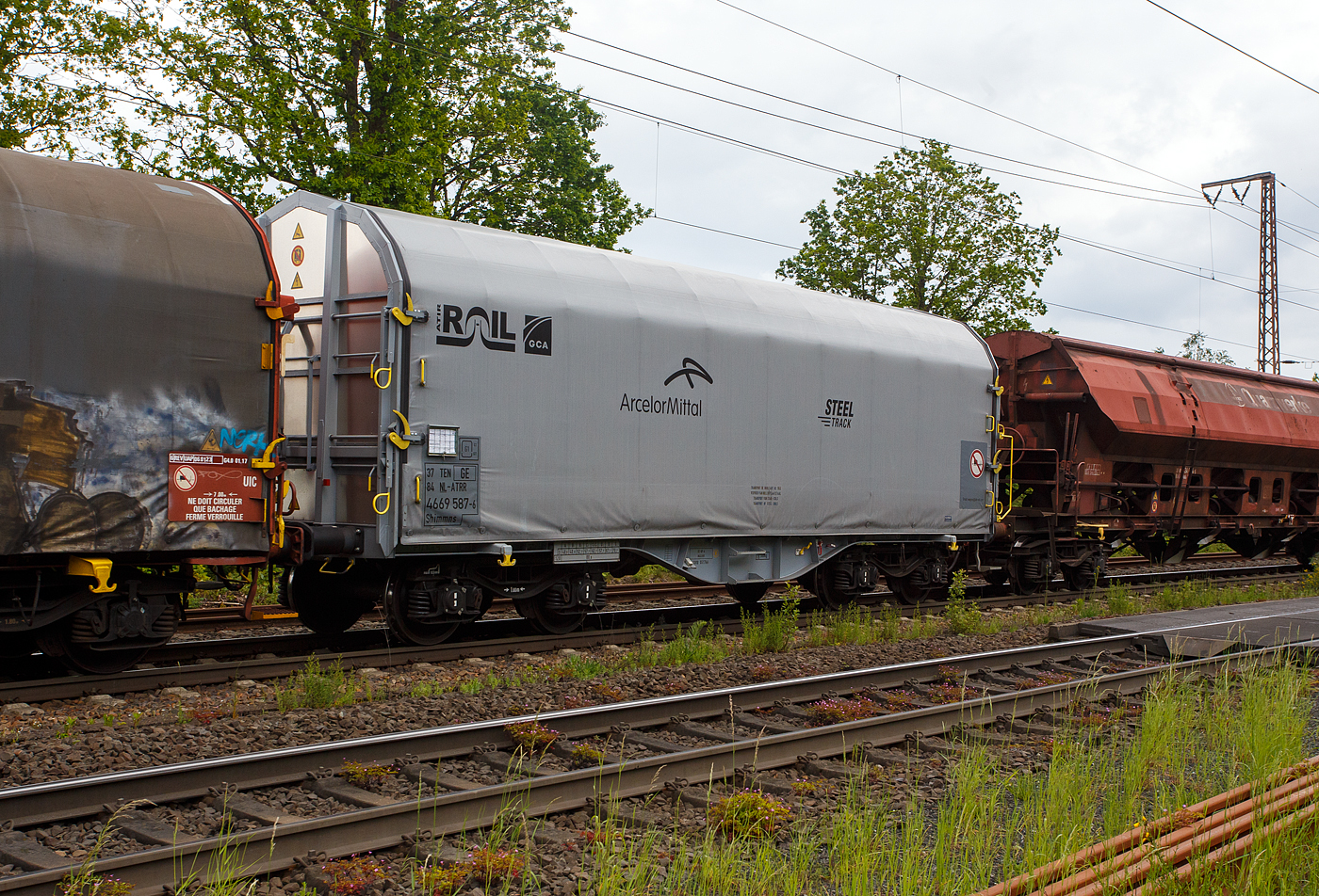 Vierachsiger Drehgestell-Flachwagen mit verschiebbarem Planenverdeck und Lademulden für Coiltransporte, 37 84 4669 587-6 NL-ATRR der Gattung Shimmns, des französischen Waggonvermieters ATIR-RAIL (Paris), vermietet an  ArcelorMittal S.A., 22 Mai 2024 im Zugverband bei einer Zugdurchfahrt in Wilnsdorf-Rudersdorf.