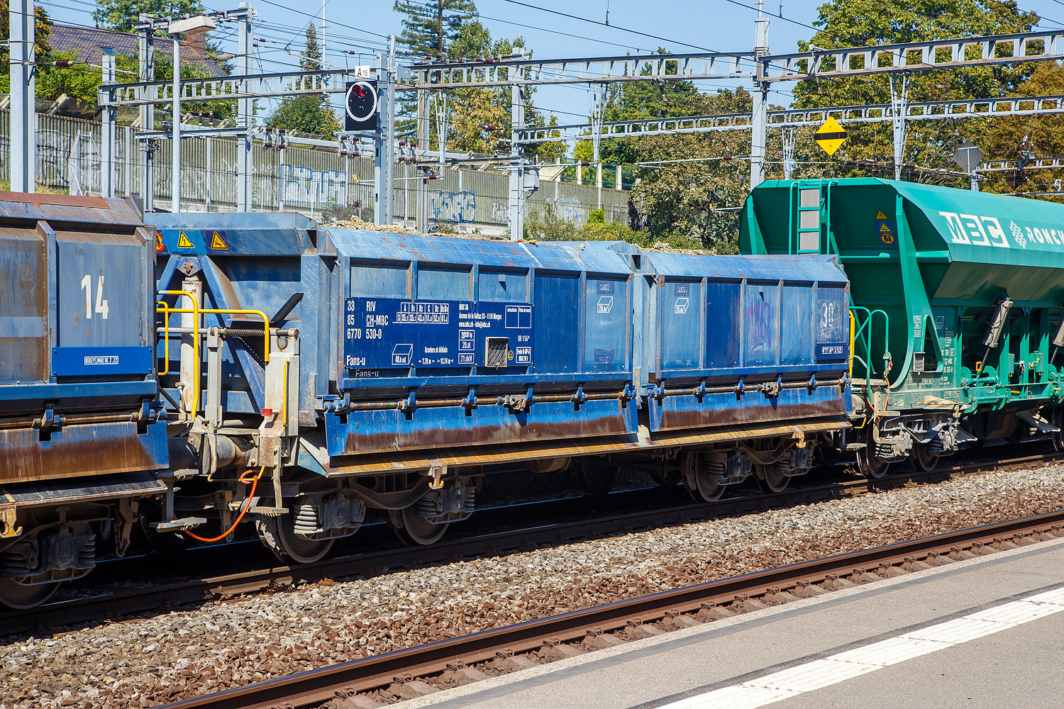 Vierachsiger zweimuldiger offener Drehgestell-Sch�ttgutkippwagen mit elektrohydraulischer Bet�tigung (Zweiseiten-Kastenkipper), 33 85 6770 530-0 CH-MBC, der Gattung Fans-u, der MBC SA (Transports de la r�gion Morges–Bi�re–Cossonay, ex BAM - Compagnie du Chemin de fer Bi�re–Apples–Morges am 07 September 2023 im Bahnhof Morges, hier beladen mit Aushubmaterial-

Der zweimuldige Drehgestell-Sch�ttgutkippwagen ist f�r den Transport von feuchtigkeitsunempfindlichen Sch�ttg�tern wie z.B. Splitt, Kies, Schotter, erdfeuchtem Sand, Bodenaushub oder Bauschutt vorgesehen. Der Wagen besitzt einen elektrohydraulischen Kippantrieb.

TECHNISCHE DATEN (laut Anschriften):
Spurweite: 1.435 mm (Normalspur)
Achsanzahl: 4 in zwei Drehgestellen
L�nge �ber Puffer: 12.740 mm
Drehzapfenabstand: 7.700 mm
Achsabstand im Drehgestell: 1.800 mm
Laufraddurchmesser: 920 mm (neu)
Laderaum: 2 x 20,0 m� = 40,0 m�
Entlade Kippwinkel: 55�
H�chstgeschwindigkeit: 100 km/h (beladen) / 120 km/h (leer)
Maximales Ladegewicht: 61,4 t (ab Streckenklasse D3)
Eigengewicht: 28.520 kg
Kleinster befahrbarer Gleisradius: R 45 m
Bremse: Frein O-GP-A (LL)
Bremssohle: IB 116
Intern. Verwendungsf�higkeit: RIV

Bedeutung der Gattung Fans-u:
F = Offener G�terwagen in Sonderbauart
a = Mit 4 Achsen
n = Tragf�higkeit �ber 60 t
s = H�chstgeschwindigkeit 100 km/h
u = Elektro-hydraulische Kippvorrichtung
