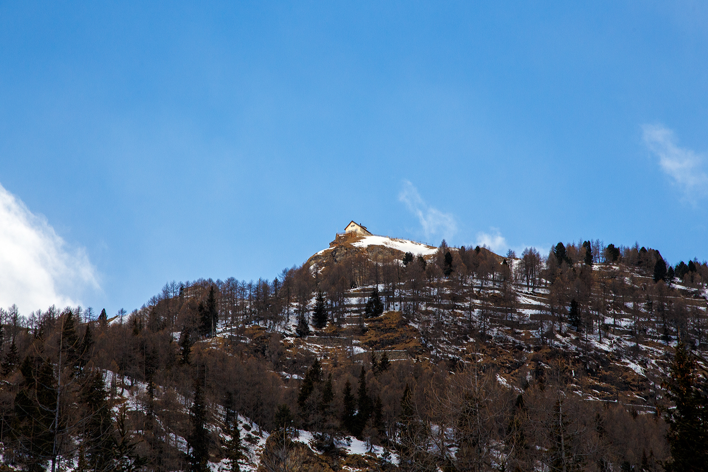 Wir fahren am 20 Februar 2017 mit einem  RhB Bernina-Regio von Tirano nach St. Moritz, oberhalb von Cavaglia kann man bereits auf Alp Grüm sehen. Oben auf der Spitze thront das Casa Alpina Belvedere, links unterhalb durch die Bäume kann man den RhB Bahnhof Alp Grüm erahnen.