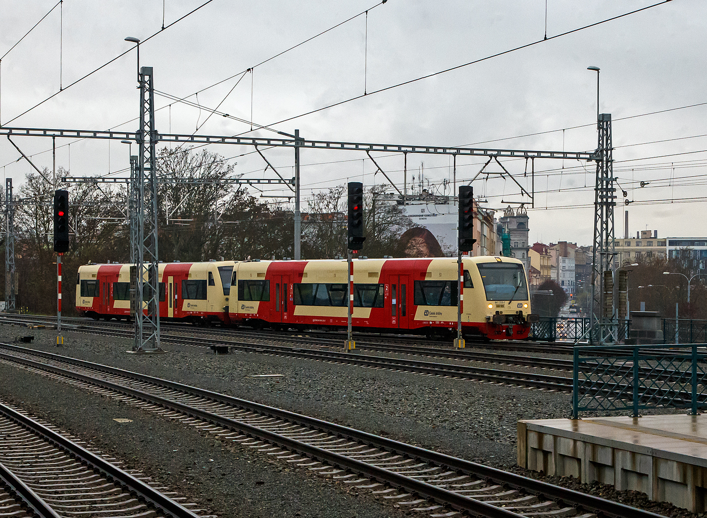 Zwei gekuppelte STADLER Regio-Shuttle RS1 bzw. ČD RegioSpider der ČD (Česk drhy) erreichen am 24.11.2022 den Hauptbahnhof Pilsen (Plzeň hlavn ndra). 

An der Farbgebung kann man es noch erkennen, es sind zwei ehemalige deutsche Triebwagen der Hohenzollerische Landesbahn (HzL). Vorne 841 215-7 (CZ- ČD 95 54 5841 215-7), ex 95 80 0650 618-1 D-HZL, ex HZL VT 215 und hinten der 841 216-5 (CZ- ČD 95 54 5841 216-5), ex 95 80 0650 619-9 D-HZL, ex HZL VT 216. Diese beiden Regio-Shuttle RS1 wurden 1997 von ADtranz (ABB Daimler Benz Transportation) in Berlin (heute Stadler Pankow), unter den Fabriknummern 36578 und 36579, gebaut. Ende 2020 wurden 22 der 24 ex HZL Regioshuttle von der SWEG, ber den Hndler HEROS (Helvetic Rolling Stock GmbH) in Rheinfelden, an die ČD verkauft. Die beiden verbleibenden Fahrzeuge (HZL) werden durch HEROS selbst vermietet. 

Die Fahrzeuge der ČD-Baureihe 841 sind niederflurige Dieseltriebwagen des tschechischen Eisenbahnverkehrsunternehmens Česk drhy (ČD), die seit 2012 im Regionalverkehr zum Einsatz kommen. Sie entsprechen dem in Deutschland weit verbreiteten und bewhrten Typ Stadler Regio-Shuttle RS1. Seit Januar 2013 vermarkten die ČD die Zge als RegioSpider. Diese lteren ehemaligen HZL-Fahrzeuge entsprechen nicht ganz den Daten der neueren Fahrzeuge, die direkt fr die ČD gebaut wurden, daher werden sie auch als BR 841.2 gefhrt.

Der Regioshuttle ist ein vom Unternehmen ADtranz (ABB Daimler Benz Transportation) entwickelter und gebauter Dieseltriebwagen neuer Generation. Durch die bernahme der ADtranz-Sparte durch Bombardier, durfte diese den Regioshuttle aus kartellrechtlichen Grnden seit 2001 nicht mehr fertigen, somit wurde die Rechte und Produktion an Stadler Rail abgegeben.

TECHBISCHE DATEN:
Spurweite: 1.435 mm
Achsfolge: B'B'
Lnge ber Puffer: 25.500 mm
Lnge Wagenkasten: 24.260 mm
Drehzapfenabstand: 17.100 mm
Achsstand im Drehgestell: 1.800 mm
Federung: 2 luftgefederte Triebdrehgestelle
Eigengewicht: 42 t
Motor: 2 Stck 12l Dieselmotoen mit je 257 KW (350 PS)
Leitungsbertragung: hydromechanisch
Getriebe: 2 Stck Voith-Diwabus Getriebe U 86
Hchstgeschwindigkeit: 120 km/h
Beschleunigung: 1,2 m/s
Einstiegshhe:  600 mm
Fahrgastraum: klimatisiert
Pltze: 70 Sitzpltze, davon 18 als Klappsitze, 88 Stehpltze
Niederfluranteil: 65% bezogen auf die Lnge des Fahrgastraumes
Tren: Vier 2-flgelige Automatik-Schwenkschiebetren
Einstiegshilfe je Fahrzeugseite: Rollstuhl-Hublift an Tr L1 und R1
WC: behindertengerecht