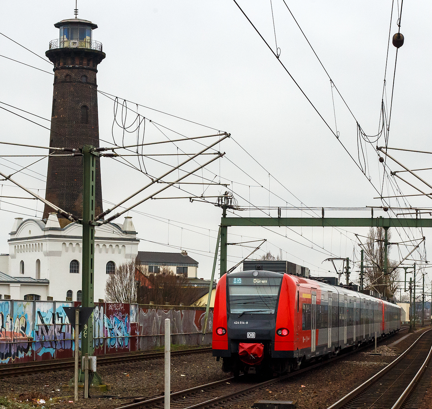 Zwei gekuppelte vierteilige modernisierte Elektro-Triebwagen der Baureihe 424/434 der S-Bahn Köln (Betreiber DB Regio NRW) verlassen am 30 Dezember 2024 als S 19 nach Düren den Bahnhof Köln-Ehrenfeld. Vorne der ET 424 032-1 / 434 032-9 / 434 532-8 / 424 532-0 und hinten der ET 424 014-9 / 434 014-7 / 434 514-6 / 424 514-8.

Im Hintergrund der 44 m hohe Leuchtturm Heliosturm, 230 Kilometer vom nächsten Meer entfernt. Der Turm wurde an der nordwestlichen Ecke der ehemaligen Werkshalle der Helios AG errichtet. Auf der auskragenden Plattform des Heliosturms befand sich bis zum Zweiten Weltkrieg ein Versuchsleuchtfeuer. Die Helios AG, ein deutscher Pionier der Elektrotechnik, baute neben Elektrogeräten auch die elektrische Ausrüstung für Leuchttürme. Mit der Leuchtfeuertechnik von Helios wurden z.B. die Leuchttürme Borkum, Campen, Roter Sand und Wangerooge ausgerüstet.