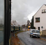 Gezogen von der schsischen VII K (Altbau) 99 1761-8 der „Lnitzdackel“  bzw. der Dampfzug der Lnitzgrundbahn am 07.12.2022 in Radebeul die Meiner Strae und somit bald den direkt dahinter liegenden Haltepunkt Weies Ro. Die Schranken sind schon unten und so muss auch der NGT 6 DD Niederflur-Gelenktriebwagen der Dresdner Straenbahnlinie 4 halten