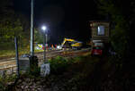 Blick auf die Baustelle Bahnhof Herdorf am Abend des 26 Oktober 2025 (21:30 Uhr). Der Liebherr Zweiwegebagger A 922 Rail Litronic mit Abstützpratzen, Kleinwagen Nr. D-KAF 99 80 9904 795-8 (KAF Interne Nr. 10016), der KAF Falkenhahn Bau AG (Kreuztal), räumt schonmal die Baustelle. Zwischen den Gleisen gelagertes Material wird auf den Lagerplatz gehoben, wo es dann einem Radlader an entsprechende freie Stellen umgesetzt wird.  