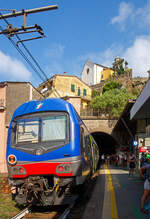 Ein Trenitalia Doppelstockzug (gezogen von einer E.464) hat am 22.07.2022, als Cinque Terre Express (Regionale) von La Spezia, via Riomaggiore, Manarola, Corniglia, Vernazza, Monterosso, nach Levanto, den Cinque Terre Bahnhof Vernazza erreicht. 

Vernazza ist eines der fünf Dörfer der Cinque Terre (Fünf Ortschaften) und verfügt, wie die anderen Dörfer, über einen Bahnhof an der Bahnstrecke Pisa–Genua (RFI Strecke-Nr. 77 / KBS 31 La Spezia–Genua). Der Bahnhof liegt zwischen zwei zweigeteilten Tunneln, jeder Bahnsteig hat seine eigenen Tunnelröhren. Wie auch in Riomaggiore passen die Bahnsteige nicht komplett unter freien Himmel, der Rest der Bahnsteige ist jeweils in einem der Tunneln. 

Oben die Kirche San Francesco (Chiesa di San Francesco) vom gleichnamentlichen Kloster Convento di San Francesco, welches hinter der Kirche liegt.
