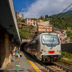 Steuerwagen voraus (geschoben von der Trenitalia E.401.011) fährt ein Trenitalia Intercity (IC) am 22.07.2022 durch den Bahnhof Vernazza (Cinque Terre) in Richtung La Spezia bzw. Pisa. 

Vernazza ist eines der fünf Dörfer der Cinque Terre (Fünf Ortschaften) und verfügt, wie die anderen Dörfer, über einen Bahnhof an der Bahnstrecke Pisa–Genua (RFI Strecke-Nr. 77 / KBS 31 La Spezia–Genua). Der Bahnhof liegt zwischen zwei zweigeteilten Tunneln, jeder Bahnsteig hat seine eigenen Tunnelröhren. Wie auch in Riomaggiore passen die Bahnsteige nicht komplett unter freien Himmel, der Rest der Bahnsteige ist jeweils in einem der Tunneln. 

Oben sieht man den Turm der Kirche San Francesco (Chiesa di San Francesco) vom gleichnamentlichen Kloster Convento di San Francesco, welches hinter der Kirche liegt.
