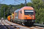 RTS Lok 2016 905 steht mit einigen Güterwagen des Gleisbauzuges zwischen zwei Bahnschranken in Enscherange.