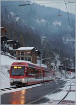 Der MGB ABDeh 4/8 2026 wartet in seinem Zugsausgangsbahnhof Fiesch auf die Abfahrt nach Zermatt, whrend im Hintergrund, schlecht sichtbar, eine Seilbahn aus Eggishorn schwebt.