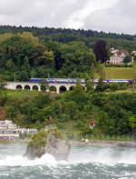 Während tobend die Wassermassen den Rheinfall bei Schaffhausen herab stürzen, fährt eine SBB Re 450 mit Doppelstock-Pendelzügen am 18.06.2016, als S 9 (Uster – Zürich HB – Schaffhausen)