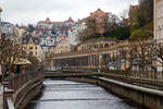 Blick über den kanalisierten Fluss Teplá (Tepl) in der Kurstadt Karlsbad (Karlovy Vary) am 18 April 2023 auf die steingemauerte Neorenaiss Mühlbrunnkolonnade (Mlýnská kolonáda), halblinks im Bild die zwei Türme der Kirchen St. Maria Magdalena (Kostel Maří Magdalény) und oben thront das bekannte Spa Hotel Imperial,

Im Inneren der größten Karlsbader Kolonnade der Mühlbrunnkolonnade sprudeln gleich fünf Mineralquellen, der Mühlbrunnen, die Rusalka-Quelle, Fürst-Wenzel-Quelle, Libussa-Quelle und Felsenquelle.

